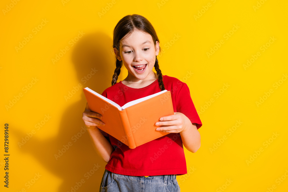 Portrait of cute little girl read book wear t-shirt isolated on yellow color background Portrait of cute little girl read book wear t-shirt isolated on yellow color background