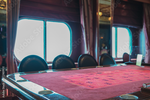 Teil von Spieltisch in Kasino auf Kreuzfahrtschiff mit Slotmaschinen im Hintergrund Glücksspiel - Casino with Roulette table and slot machines onboard ocean liner cruiseship cruise ship