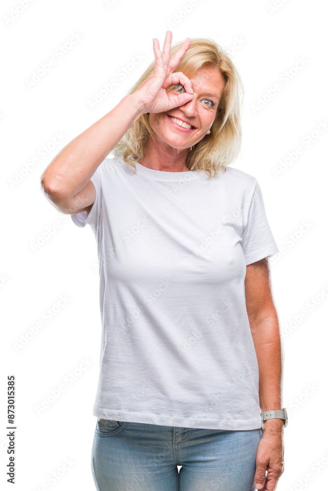 Middle age blonde woman over isolated background doing ok gesture with hand smiling, eye looking through fingers with happy face. Middle age blonde woman over isolated background doing ok gesture with hand smiling, eye looking through fingers with happy face.