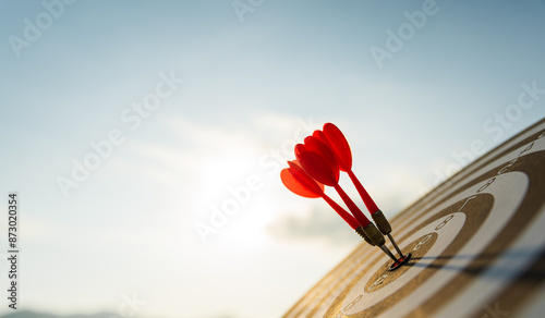 Close up shot red darts arrows in the target center on dark blue sky background. Business target or goal success and winner concept.