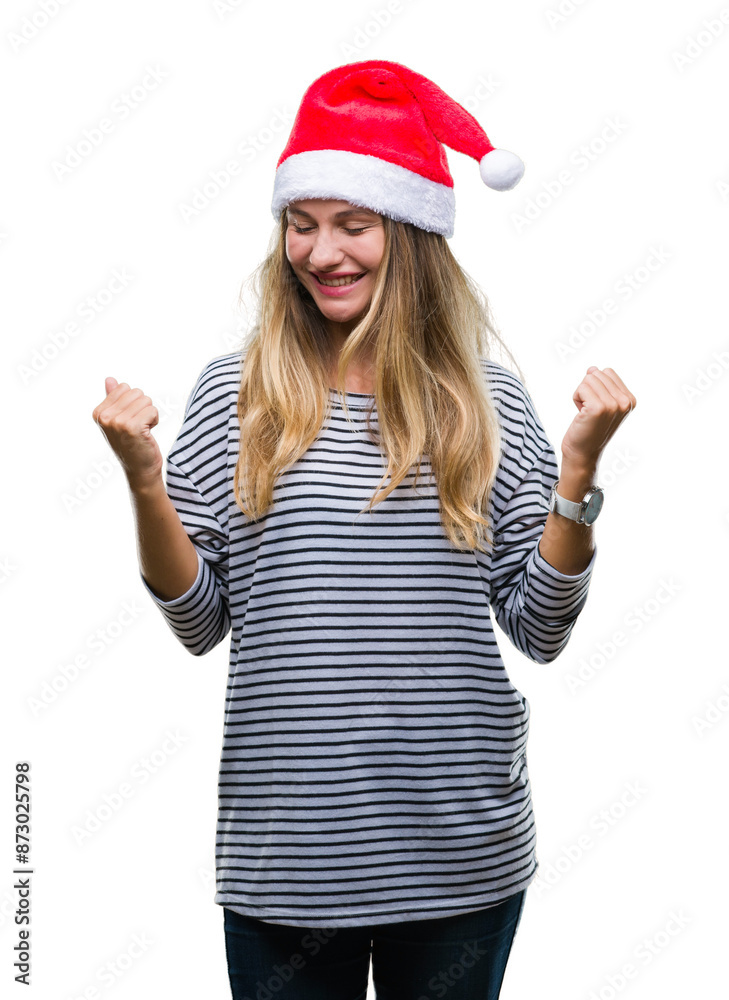Young beautiful blonde woman wearing christmas hat over isolated background very happy and excited doing winner gesture with arms raised, smiling and screaming for success. Celebration concept. Young beautiful blonde woman wearing christmas hat over isolated background very happy and excited doing winner gesture with arms raised, smiling and screaming for success. Celebration concept.