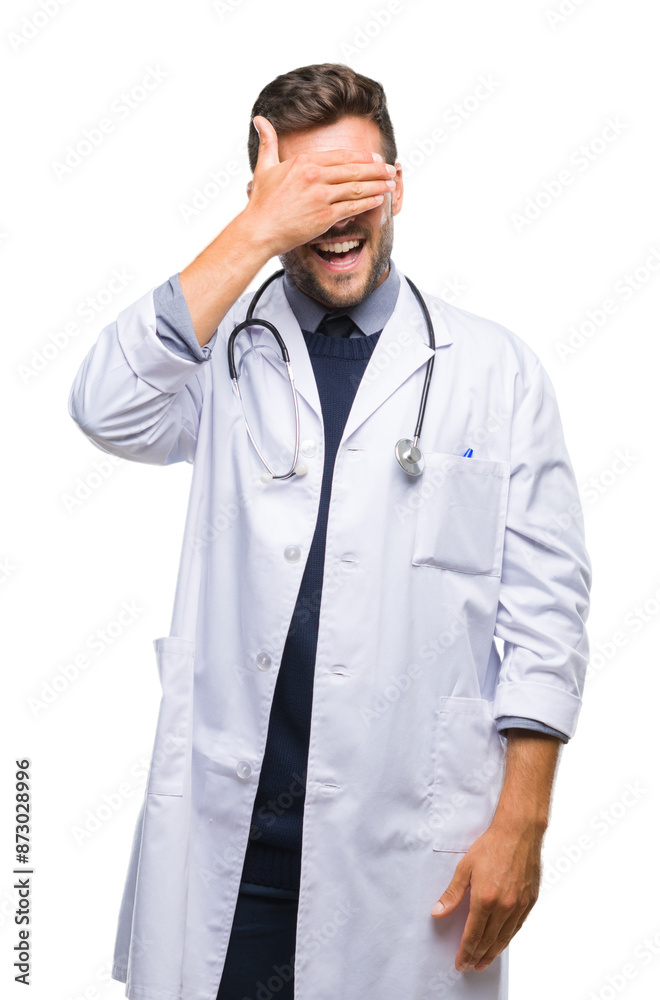 Young handsome doctor man over isolated background smiling and laughing with hand on face covering eyes for surprise. Blind concept. Young handsome doctor man over isolated background smiling and laughing with hand on face covering eyes for surprise. Blind concept.