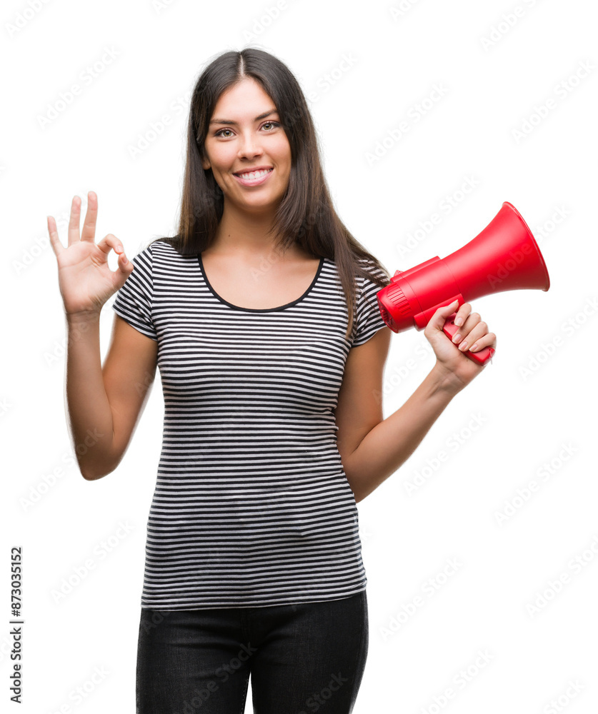 Young hispanic woman holding megaphone doing ok sign with fingers, excellent symbol Young hispanic woman holding megaphone doing ok sign with fingers, excellent symbol