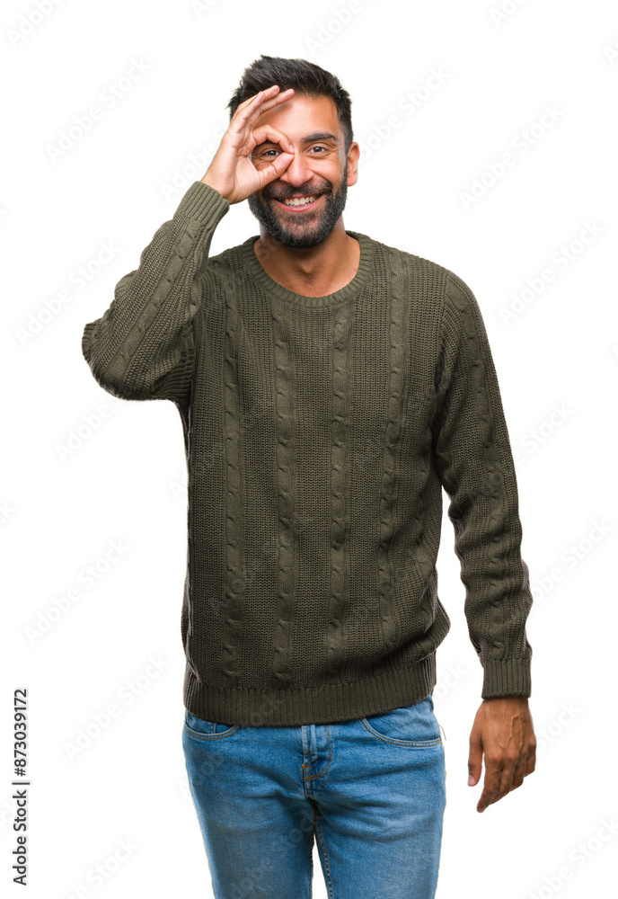 Adult hispanic man wearing winter sweater over isolated background doing ok gesture with hand smiling, eye looking through fingers with happy face. Adult hispanic man wearing winter sweater over isolated background doing ok gesture with hand smiling, eye looking through fingers with happy face.