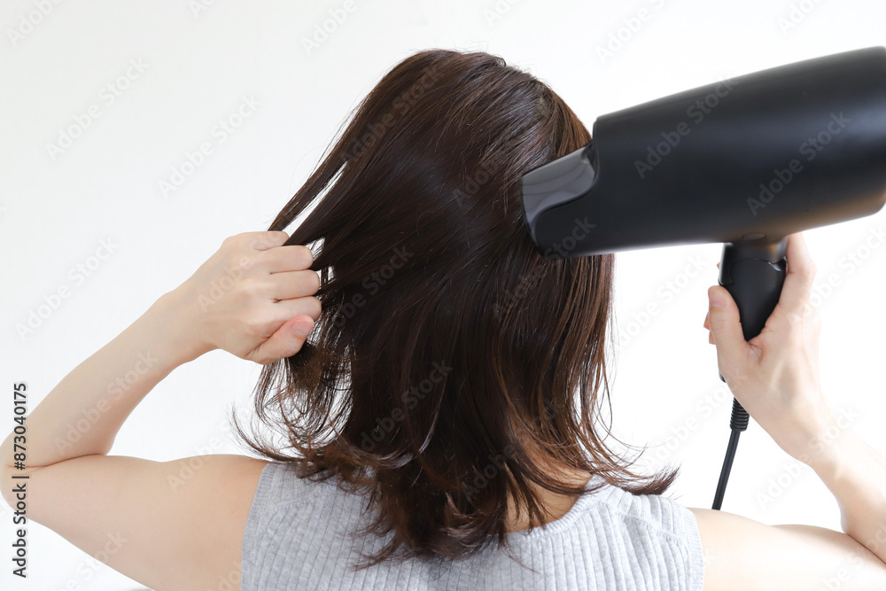 Fototapeta premium ドライヤーで髪の毛を乾かす女性