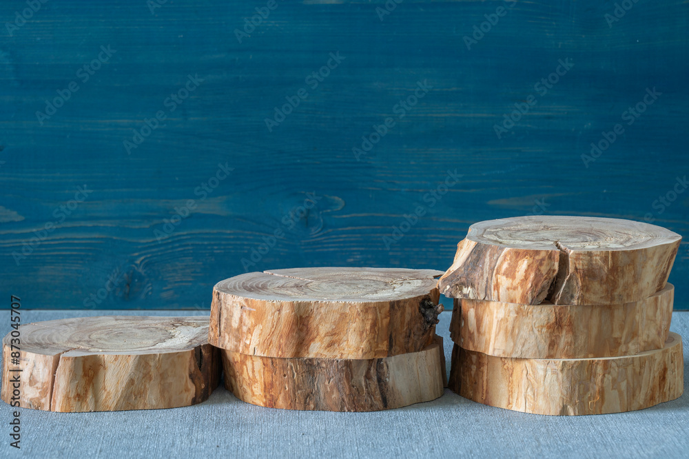 Empty podium, cross sections of apple tree on blue and background. Minimalist eco backdrop. Round natural logs. Pedestal for product advertising. Wabi sabi concept. Copy space, front view. Empty podium, cross sections of apple tree on blue and background. Minimalist eco backdrop. Round natural logs. Pedestal for product advertising. Wabi sabi concept. Copy space, front view.