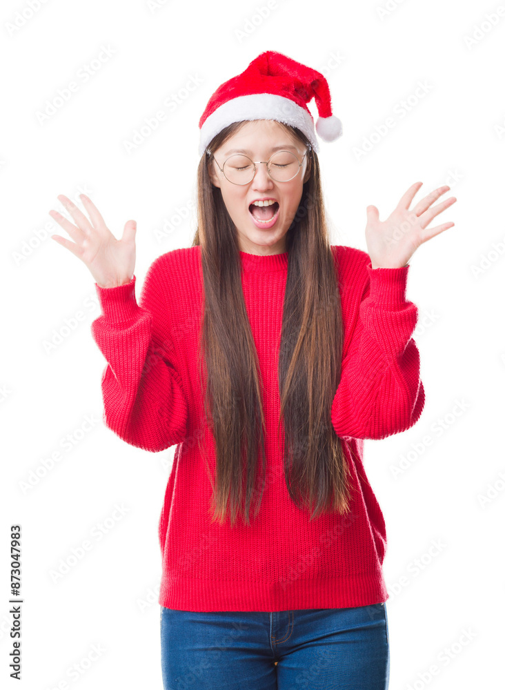 Young Chinese woman over isolated background wearing christmas hat celebrating mad and crazy for success with arms raised and closed eyes screaming excited. Winner concept Young Chinese woman over isolated background wearing christmas hat celebrating mad and crazy for success with arms raised and closed eyes screaming excited. Winner concept