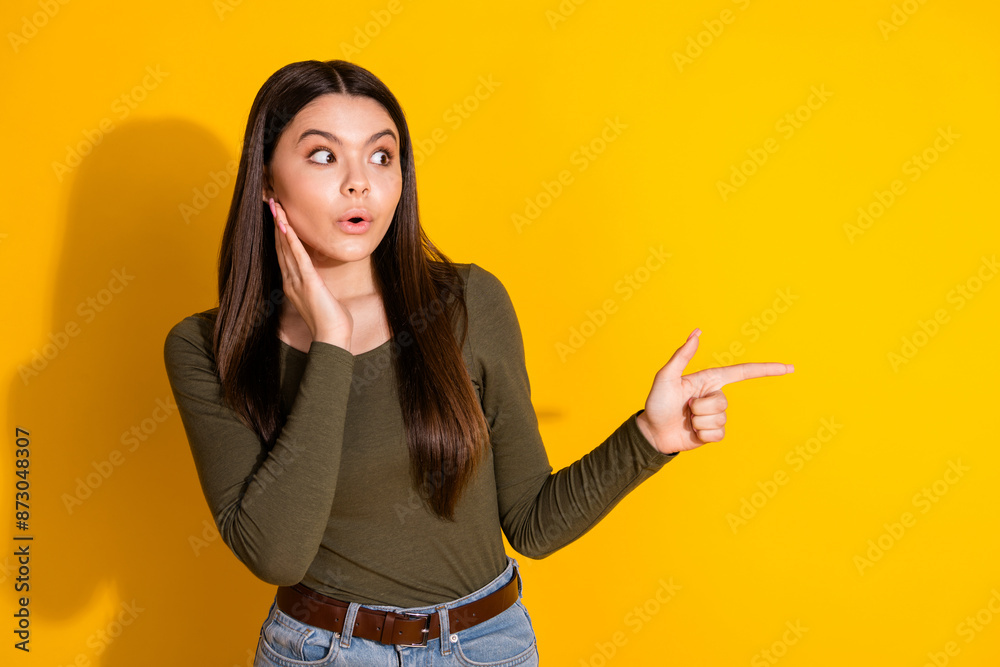 Photo portrait of attractive teen woman point amazed empty space dressed stylish khaki clothes isolated on yellow color background Photo portrait of attractive teen woman point amazed empty space dressed stylish khaki clothes isolated on yellow color background