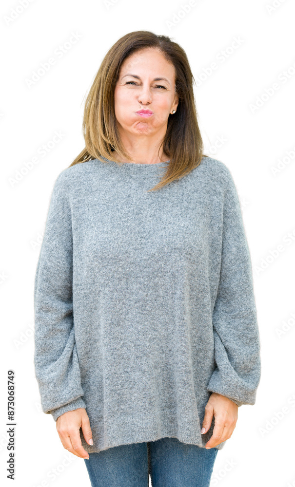 Beautiful middle age woman wearing winter sweater over isolated background puffing cheeks with funny face. Mouth inflated with air, crazy expression.