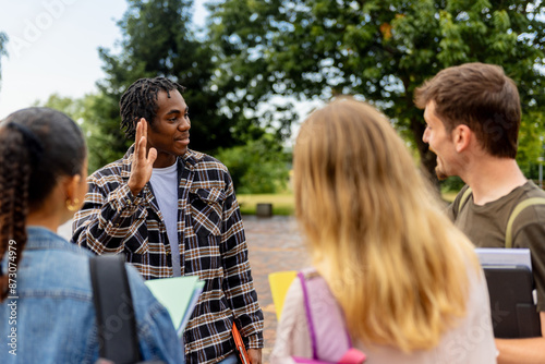 young black male high-fives another classmate as they reconnect after the vacations and resume college or high school classes. Multiracial group of students