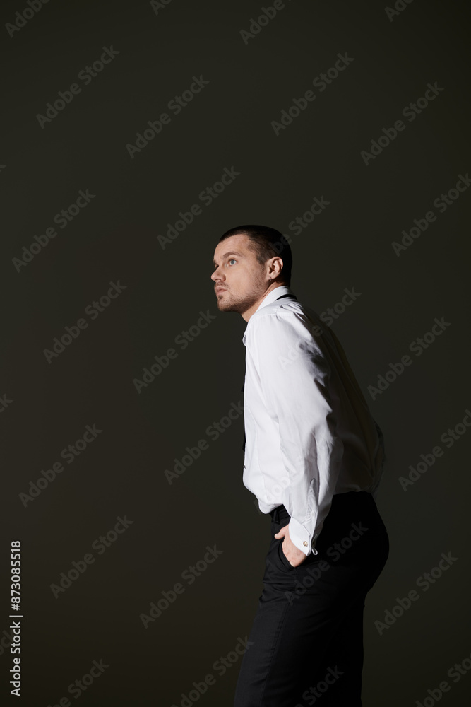 Φωτογραφία A man in a crisp white shirt and black trousers stands in a studio, gazing off to the side