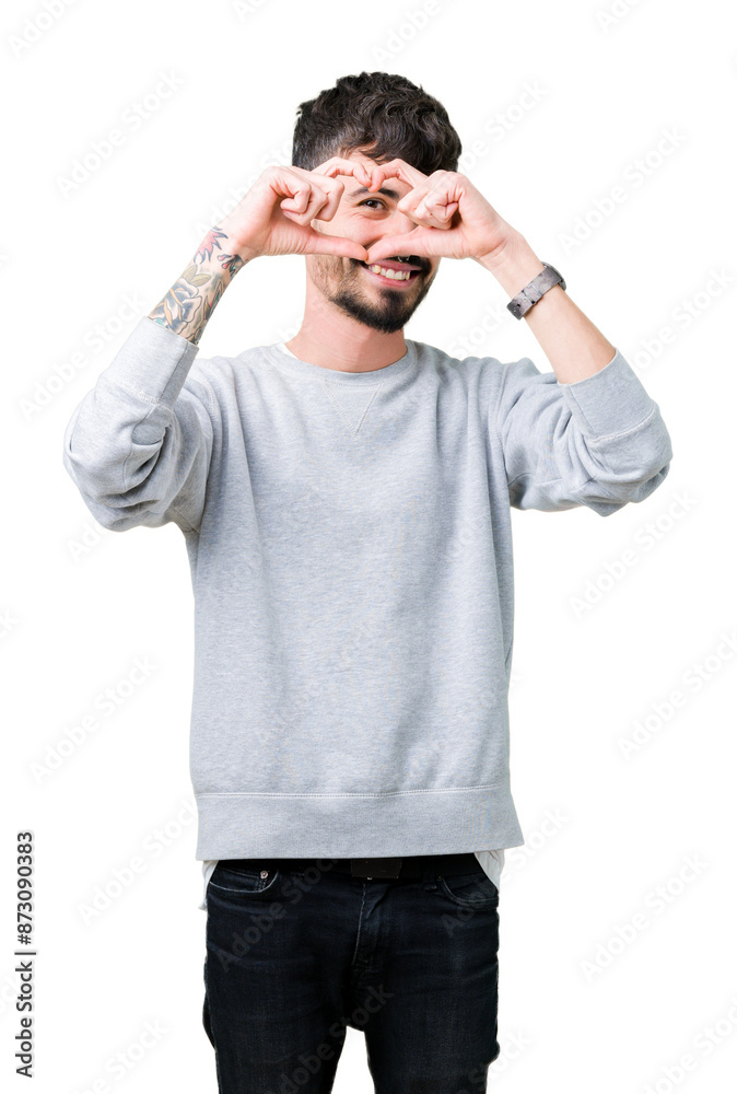 Young handsome man wearing sweatshirt over isolated background Doing heart shape with hand and fingers smiling looking through sign