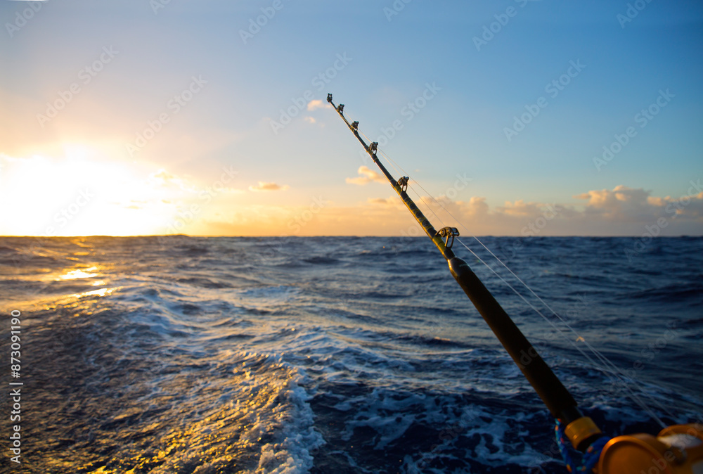 Fishing rod over waves in sea against sky during sunset Fishing rod over waves in sea against sky during sunset