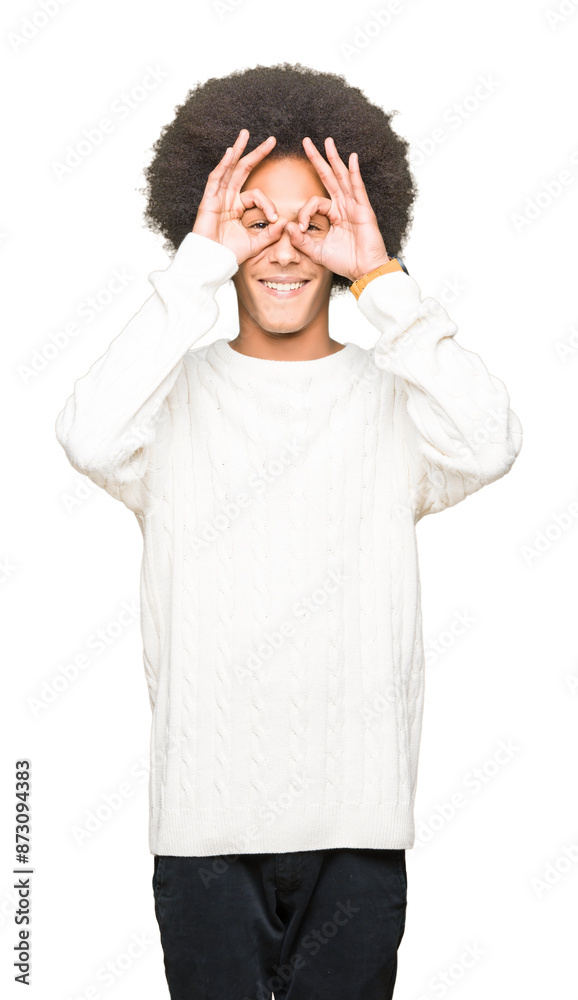 Young african american man with afro hair wearing winter sweater doing ok gesture like binoculars sticking tongue out, eyes looking through fingers. Crazy expression. Young african american man with afro hair wearing winter sweater doing ok gesture like binoculars sticking tongue out, eyes looking through fingers. Crazy expression.