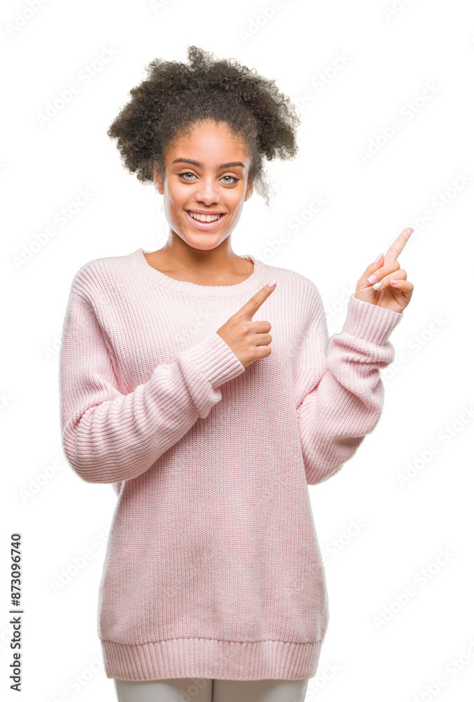 Young afro american woman wearing winter sweater over isolated background smiling and looking at the camera pointing with two hands and fingers to the side. Young afro american woman wearing winter sweater over isolated background smiling and looking at the camera pointing with two hands and fingers to the side.