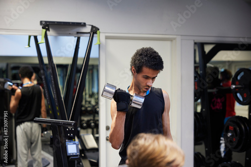 Young man exercising with dumbbells in gym