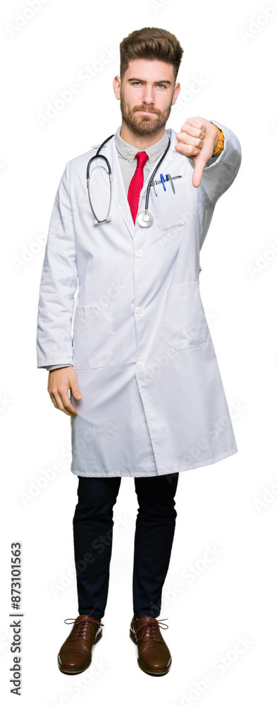 Young handsome doctor man wearing medical coat looking unhappy and angry showing rejection and negative with thumbs down gesture. Bad expression. Young handsome doctor man wearing medical coat looking unhappy and angry showing rejection and negative with thumbs down gesture. Bad expression.