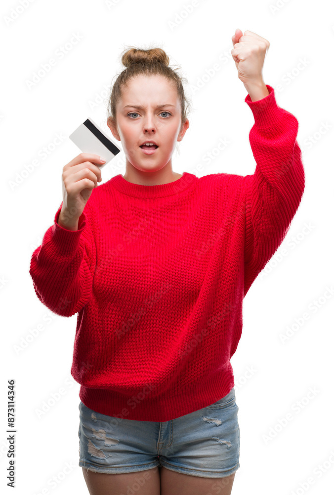 Young blonde woman holding credit card annoyed and frustrated shouting with anger, crazy and yelling with raised hand, anger concept