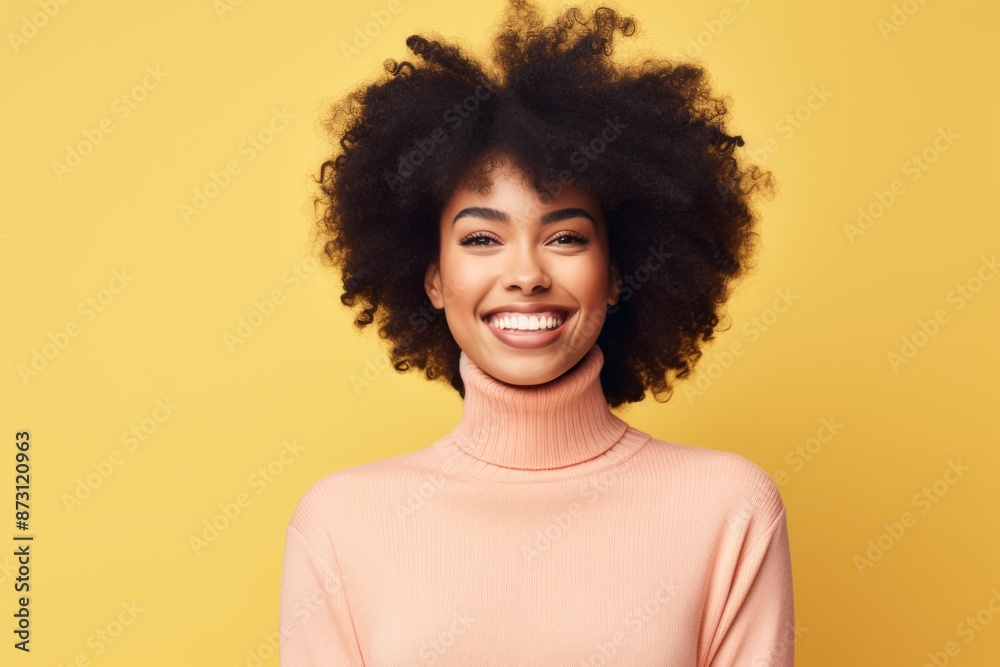 Portrait of a happy afro-american woman in her 20s wearing a classic turtleneck sweater in front of pastel yellow background