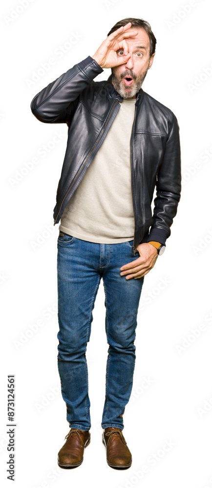 Middle age handsome man wearing black leather jacket doing ok gesture shocked with surprised face, eye looking through fingers. Unbelieving expression. Middle age handsome man wearing black leather jacket doing ok gesture shocked with surprised face, eye looking through fingers. Unbelieving expression.