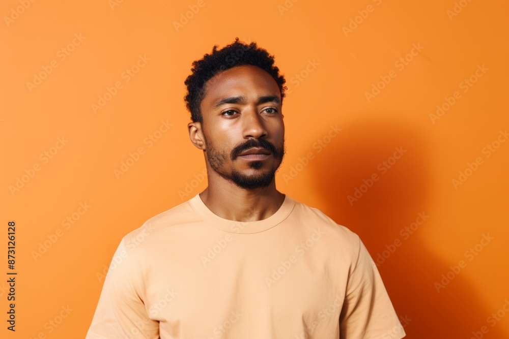 Portrait of a tender man in his 30s donning a trendy cropped top isolated on pastel orange background Portrait of a tender man in his 30s donning a trendy cropped top isolated on pastel orange background
