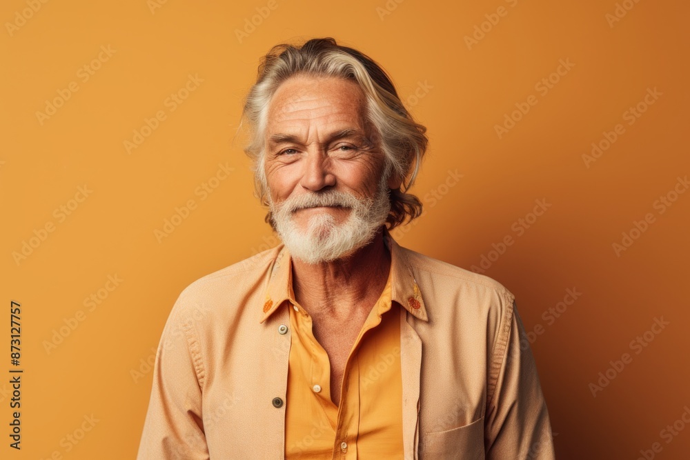 Portrait of a blissful man in his 60s donning a trendy cropped top isolated in pastel orange background Portrait of a blissful man in his 60s donning a trendy cropped top isolated in pastel orange background