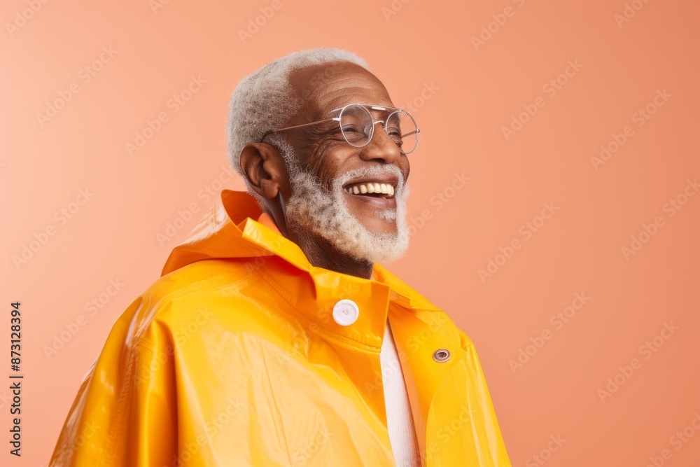 Portrait of a satisfied afro-american elderly 100 years old man wearing a vibrant raincoat over pastel orange background Portrait of a satisfied afro-american elderly 100 years old man wearing a vibrant raincoat over pastel orange background