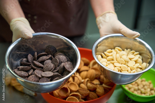 Lady pastry-cook showing bowls with chocolate and milky chips