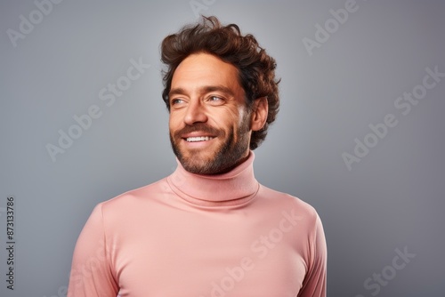 Portrait of a joyful man in his 30s wearing a classic turtleneck sweater while standing against pastel gray background