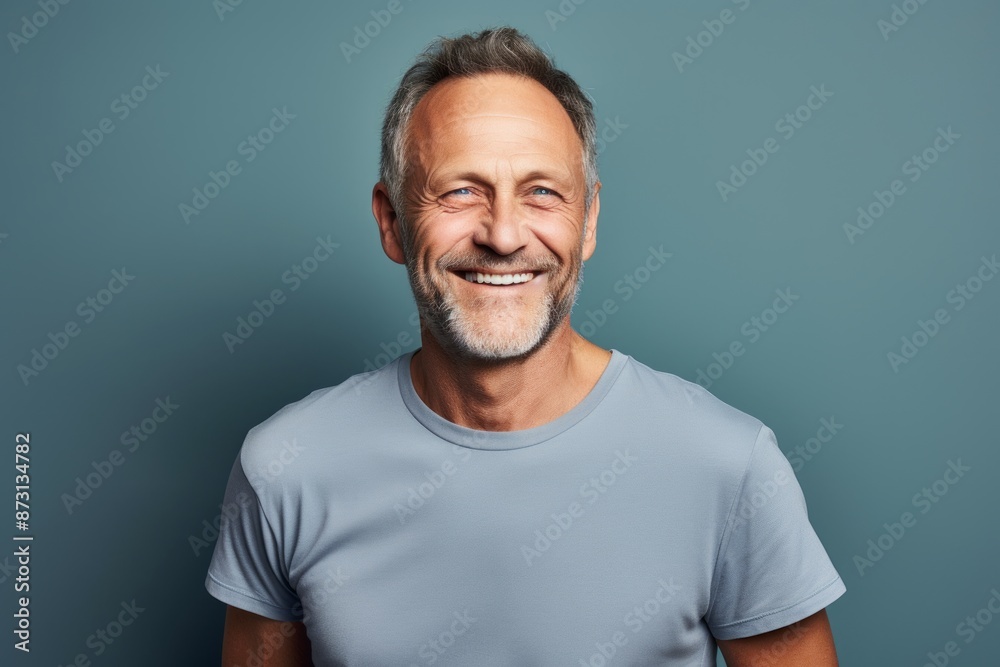 Portrait of a happy man in his 50s dressed in a casual t-shirt in front of pastel gray background Portrait of a happy man in his 50s dressed in a casual t-shirt in front of pastel gray background