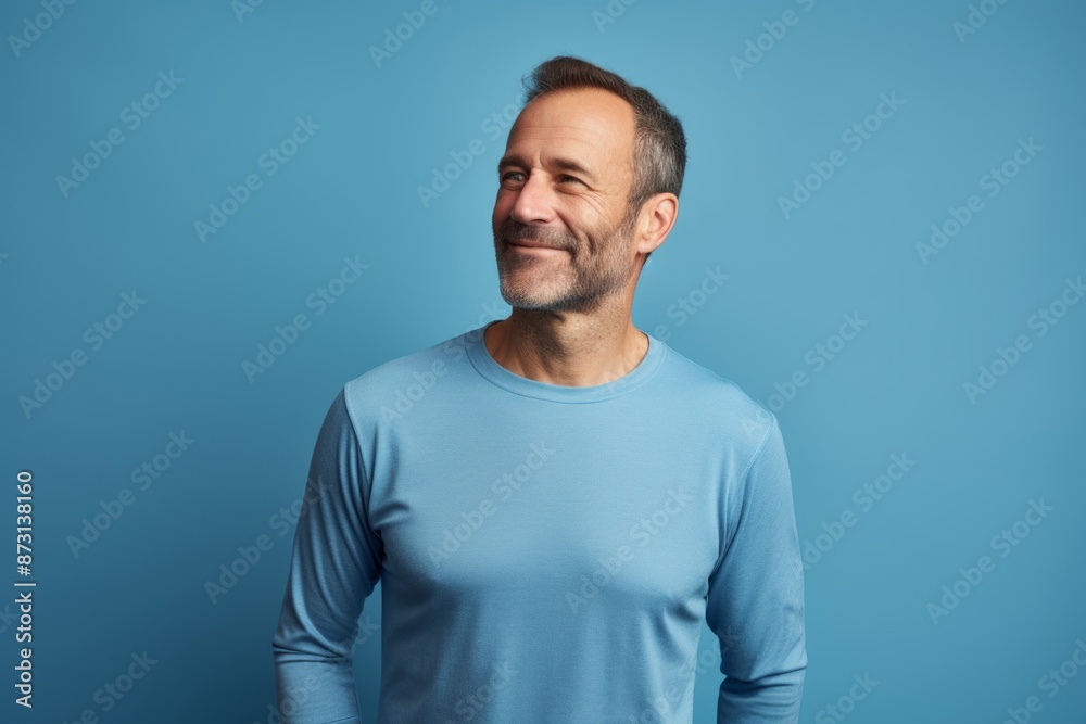 Portrait of a satisfied man in his 40s showing off a lightweight base layer on soft blue background Portrait of a satisfied man in his 40s showing off a lightweight base layer on soft blue background