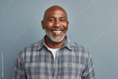 Portrait of a grinning afro-american man in his 40s dressed in a relaxed flannel shirt isolated on soft gray background