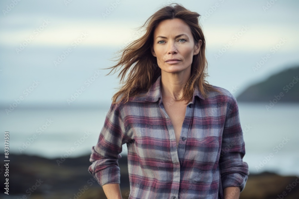 Portrait of a content woman in her 40s dressed in a relaxed flannel shirt in serene seaside background Portrait of a content woman in her 40s dressed in a relaxed flannel shirt in serene seaside background