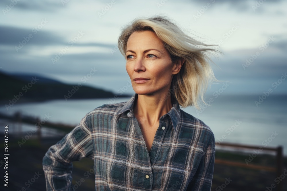 Portrait of a content woman in her 40s dressed in a relaxed flannel shirt isolated on serene seaside background Portrait of a content woman in her 40s dressed in a relaxed flannel shirt isolated on serene seaside background