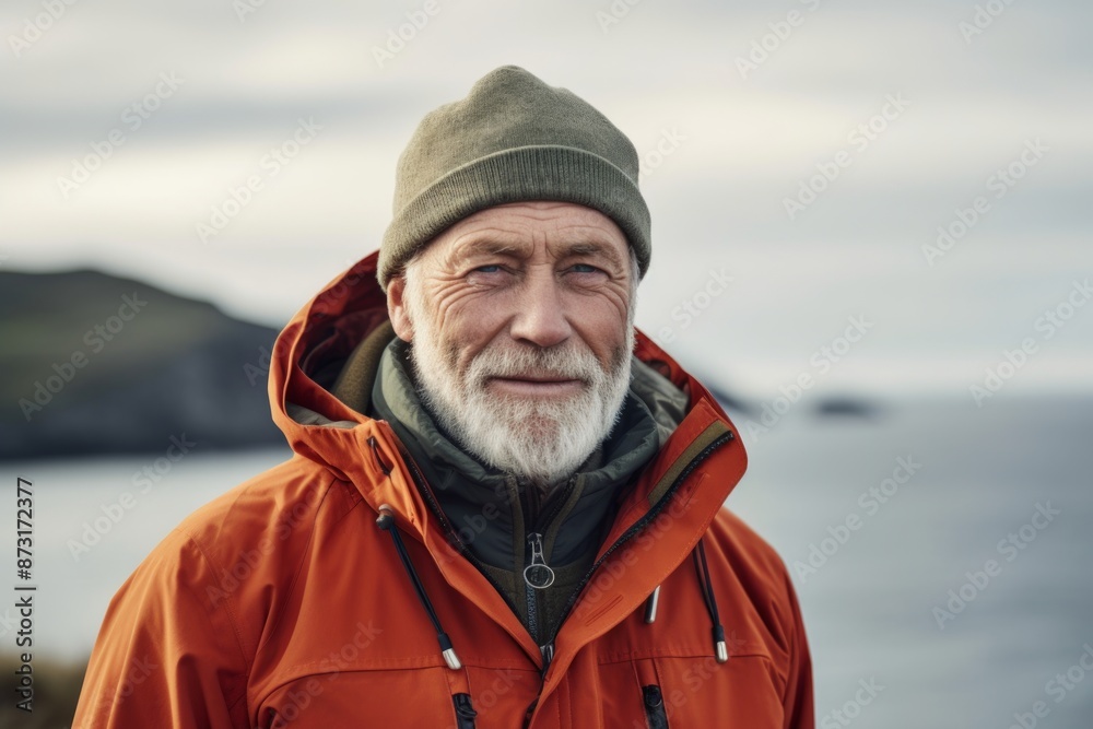 Portrait of a content man in his 60s wearing a warm parka isolated in serene seaside background Portrait of a content man in his 60s wearing a warm parka isolated in serene seaside background