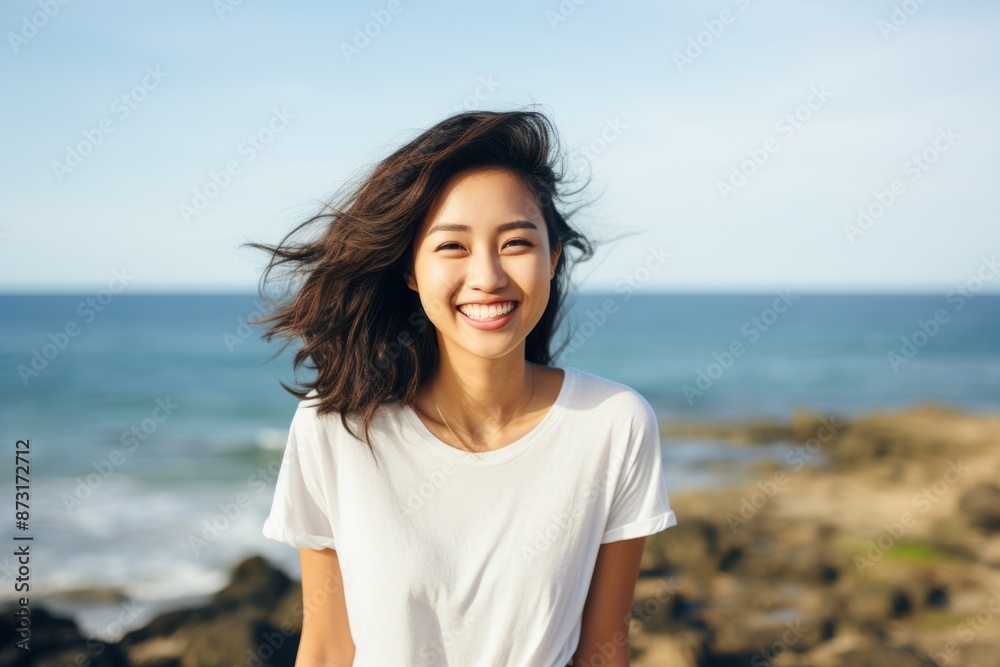 Portrait of a happy asian woman in her 20s dressed in a casual t-shirt in front of serene seaside background Portrait of a happy asian woman in her 20s dressed in a casual t-shirt in front of serene seaside background