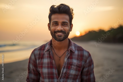 Portrait of a satisfied indian man in his 20s dressed in a relaxed flannel shirt on stunning sunset beach background