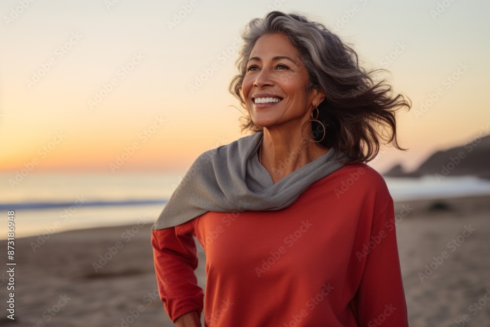 Portrait of a satisfied indian woman in her 50s showing off a thermal merino wool top in vibrant beach sunset background Portrait of a satisfied indian woman in her 50s showing off a thermal merino wool top in vibrant beach sunset background