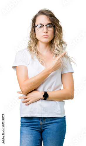 Beautiful young blonde woman wearing glasses over isolated background Pointing with hand finger to the side showing advertisement, serious and calm face