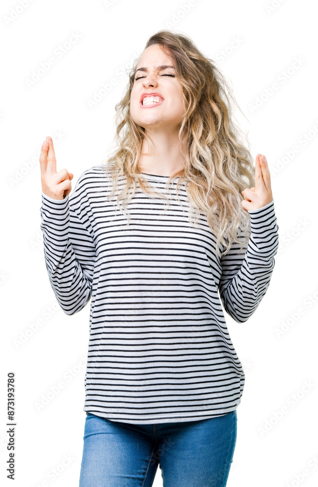 Beautiful young blonde woman wearing stripes sweater over isolated background smiling crossing fingers with hope and eyes closed. Luck and superstitious concept. Beautiful young blonde woman wearing stripes sweater over isolated background smiling crossing fingers with hope and eyes closed. Luck and superstitious concept.