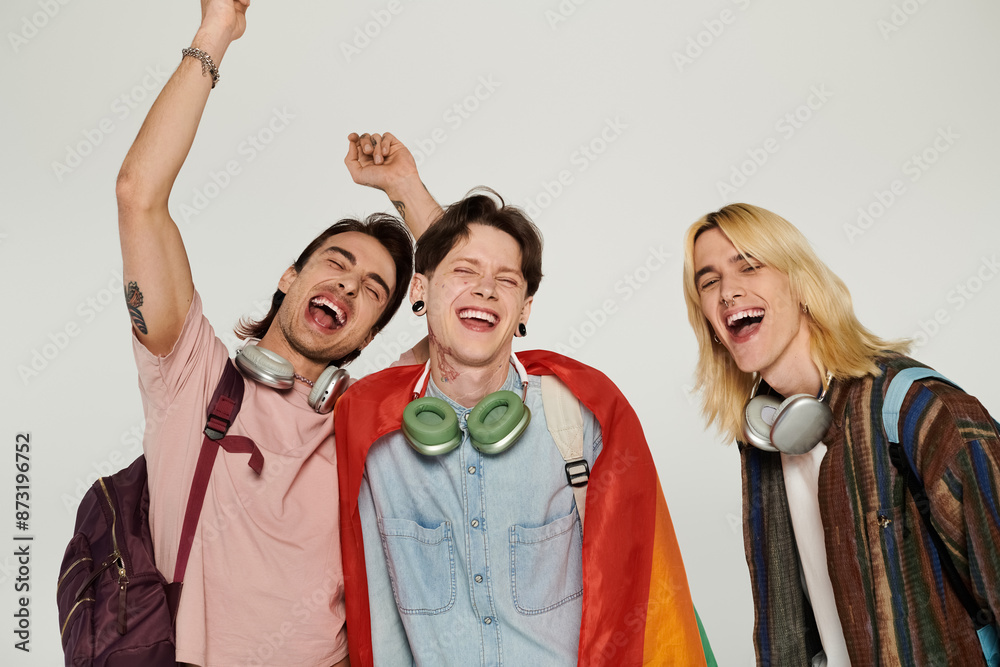 Three young students, dressed casually, pose with a rainbow flag and smiles, celebrating their friendship and inclusivity. Three young students, dressed casually, pose with a rainbow flag and smiles, celebrating their friendship and inclusivity.