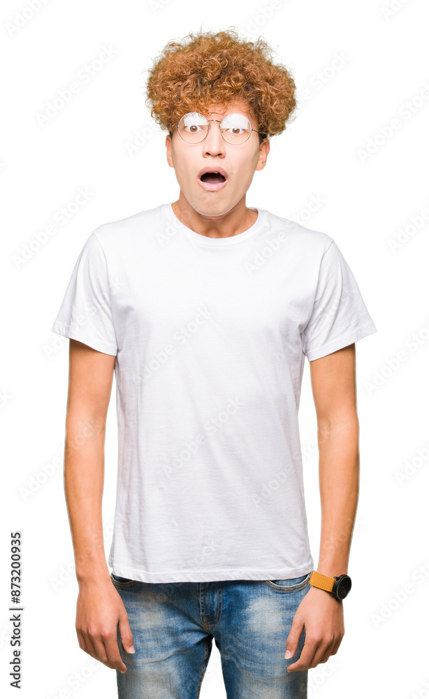 Young handsome man with afro hair wearing glasses afraid and shocked with surprise expression, fear and excited face.