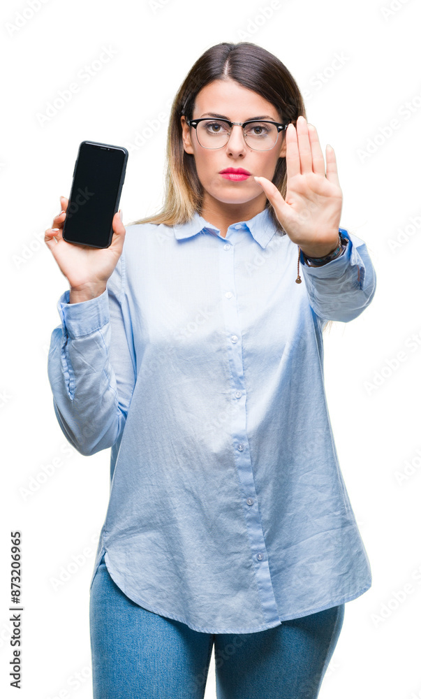 Young beautiful business woman showing blank screen of smartphone over isolated background with open hand doing stop sign with serious and confident expression, defense gesture Young beautiful business woman showing blank screen of smartphone over isolated background with open hand doing stop sign with serious and confident expression, defense gesture