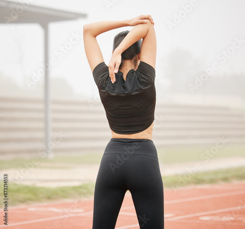 Woman, sports and stretching arms at stadium, runner and training in outdoor for fitness in routine. Female person, warm up and flexibility for muscle or athlete for wellness, getting ready and back © peopleimages.com