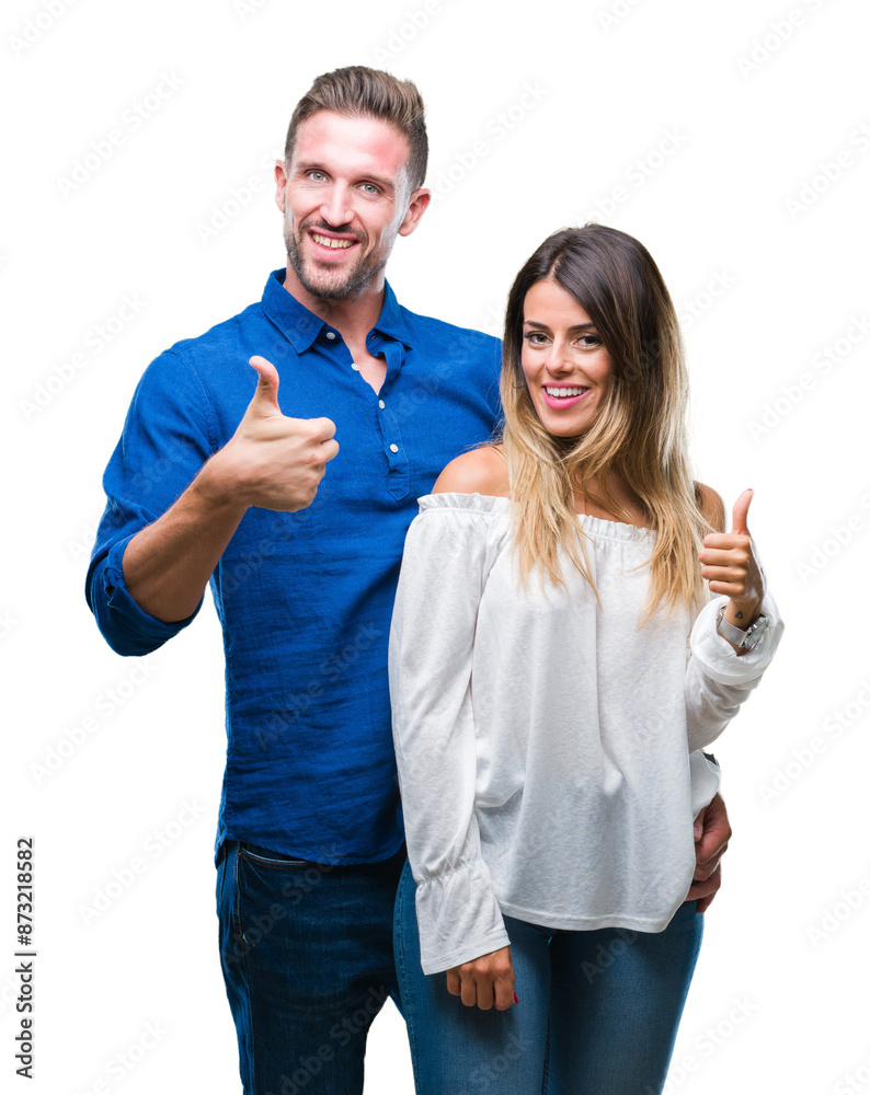 Young couple in love over isolated background doing happy thumbs up gesture with hand. Approving expression looking at the camera with showing success. Young couple in love over isolated background doing happy thumbs up gesture with hand. Approving expression looking at the camera with showing success.