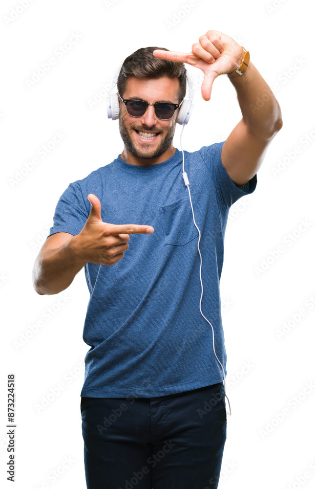 Fototapeta premium Young handsome man wearing headphones listening to music over isolated background smiling making frame with hands and fingers with happy face. Creativity and photography concept.