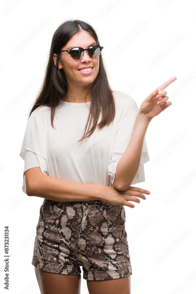 Young beautiful hispanic wearing sunglasses very happy pointing with hand and finger to the side Young beautiful hispanic wearing sunglasses very happy pointing with hand and finger to the side