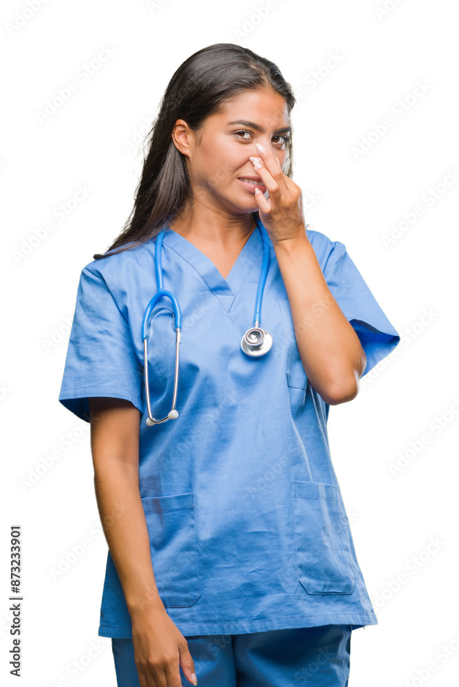 Young arab doctor surgeon woman over isolated background smelling something stinky and disgusting, intolerable smell, holding breath with fingers on nose. Bad smells concept. Young arab doctor surgeon woman over isolated background smelling something stinky and disgusting, intolerable smell, holding breath with fingers on nose. Bad smells concept.
