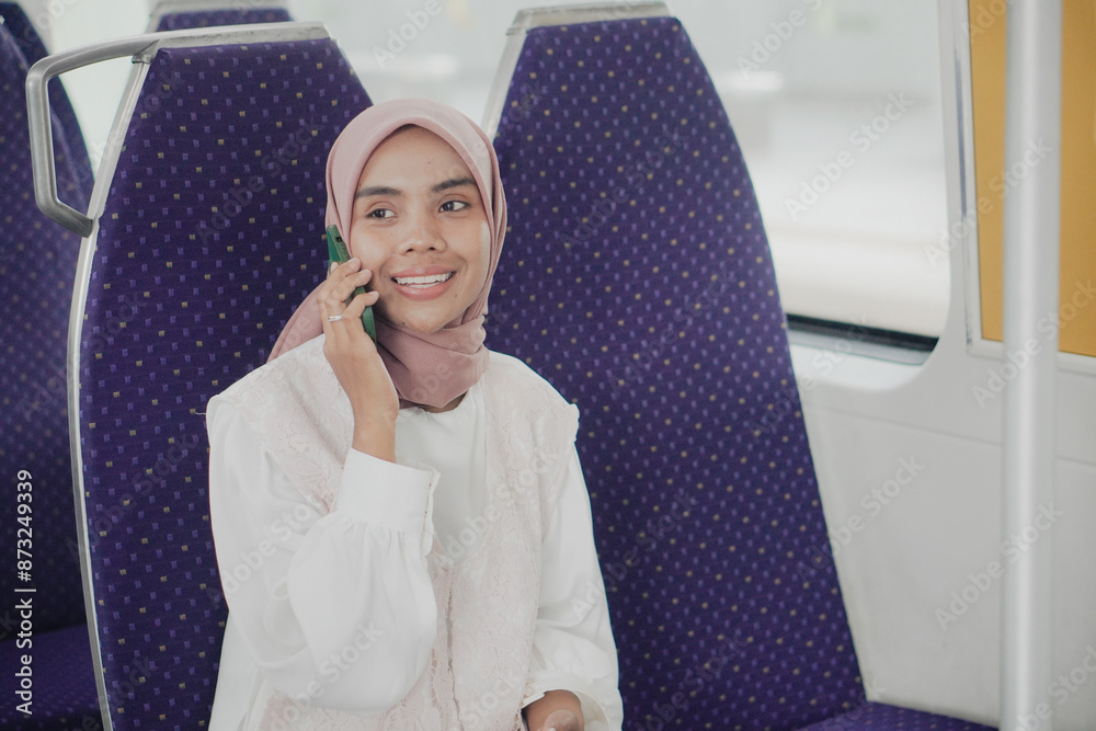 A smilling woman sitting on a train using cell phone A smilling woman sitting on a train using cell phone