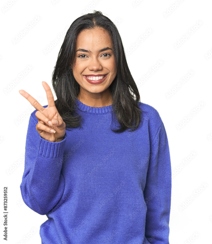Simple portrait of a young Latina showing victory sign and smiling broadly. Simple portrait of a young Latina showing victory sign and smiling broadly.